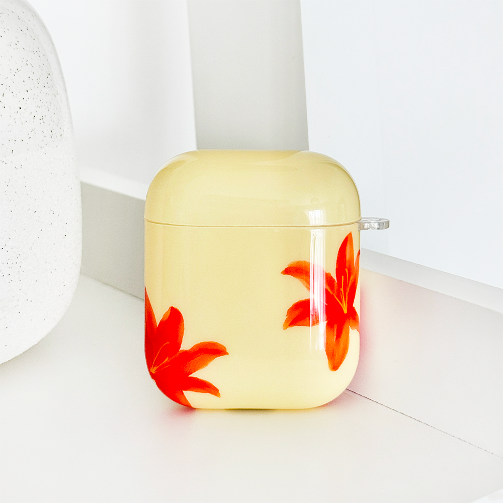 Coconut Lane Airpods Case in Island Girl Ibiza Lily pattern on a white surface next to a white textured object.