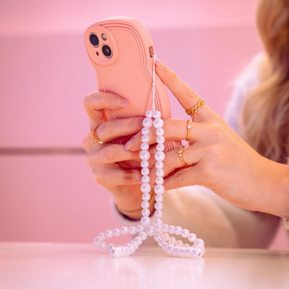 Model holding Phone Strap in a bow shape made from pearls, attached to a pink phone case.