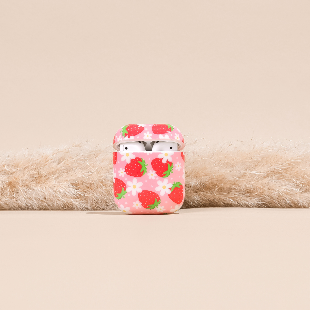 Pink Airpods case with a flower and strawberry pattern, shown holding white wireless earbuds.