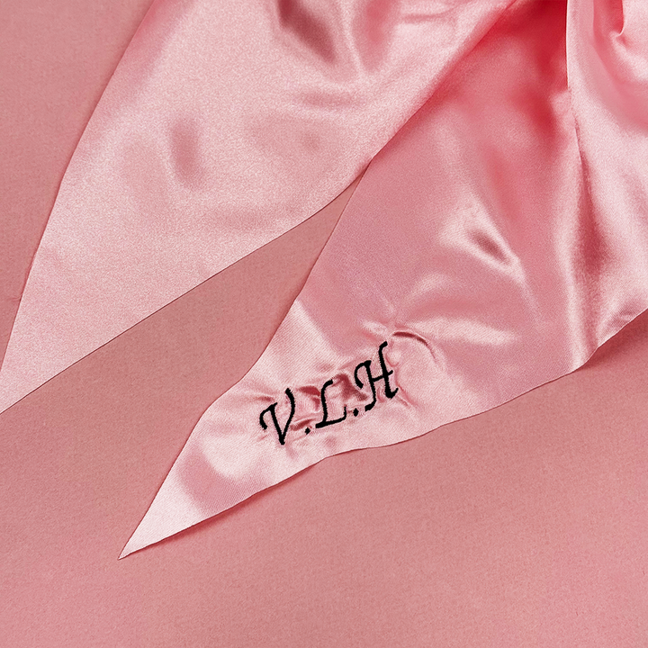 Pink satin fabric with 'V.L.A' monogram on a pink background