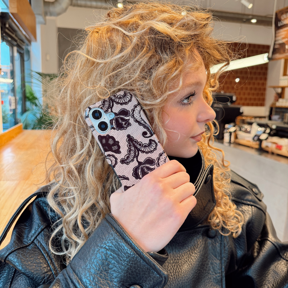 Girl on the phone in a cafe holding black lace phone case