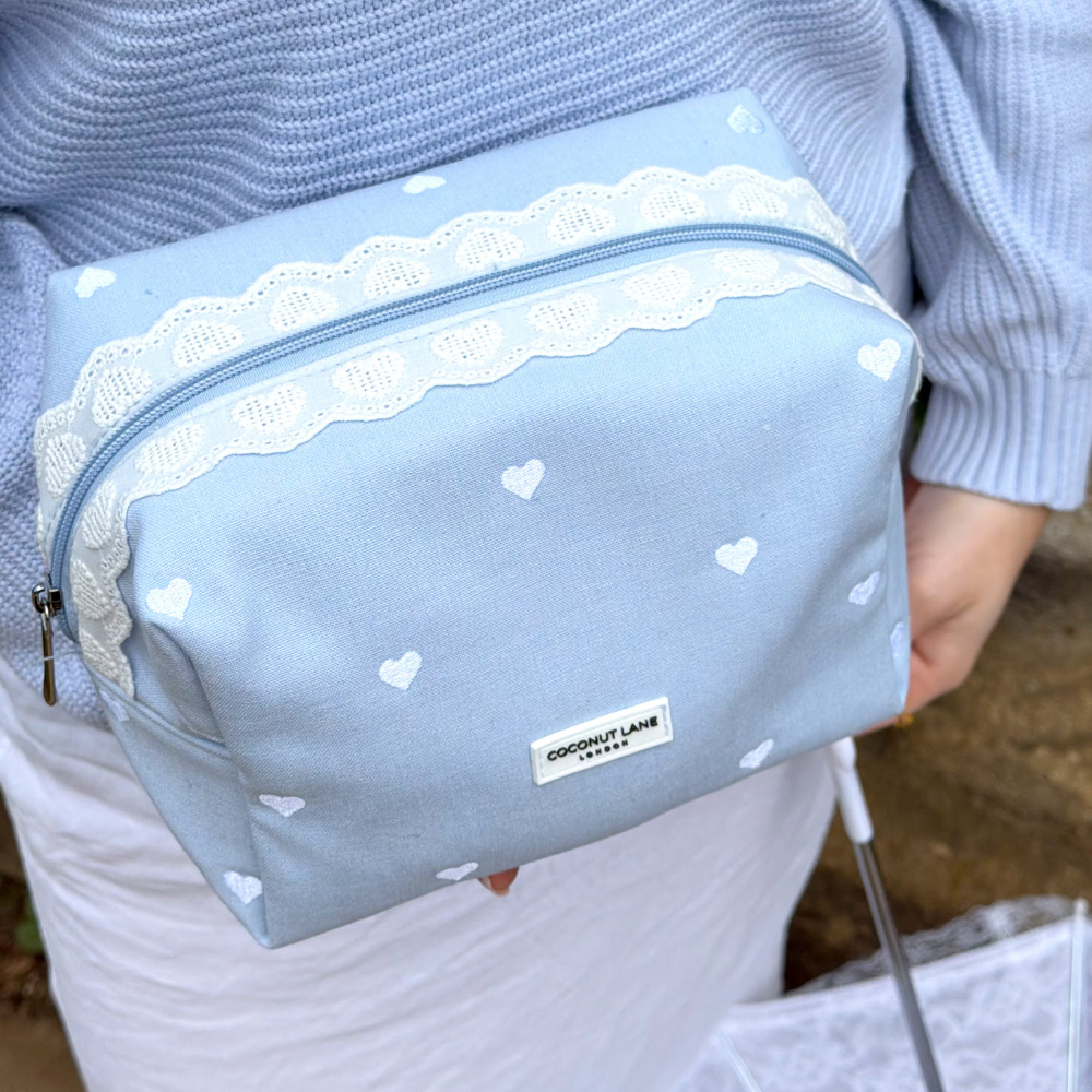 Girl in blue holding the Blue Hearts Makeup Bag with lace and white hearts