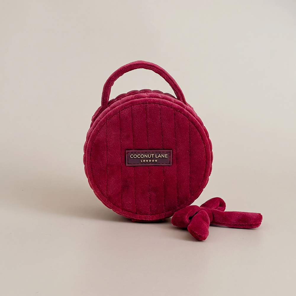 Burgundy velvet jewellery box with a quilted design, top handle, bow detail, and gold-tone hardware.