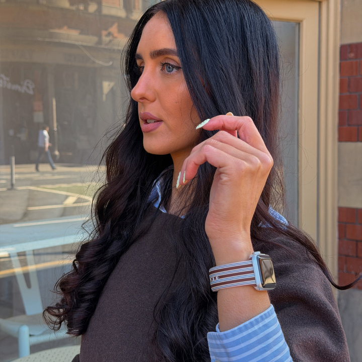Girl holding up her wrist next to her face wearing the Brown and Blue Stripe Watch Strap