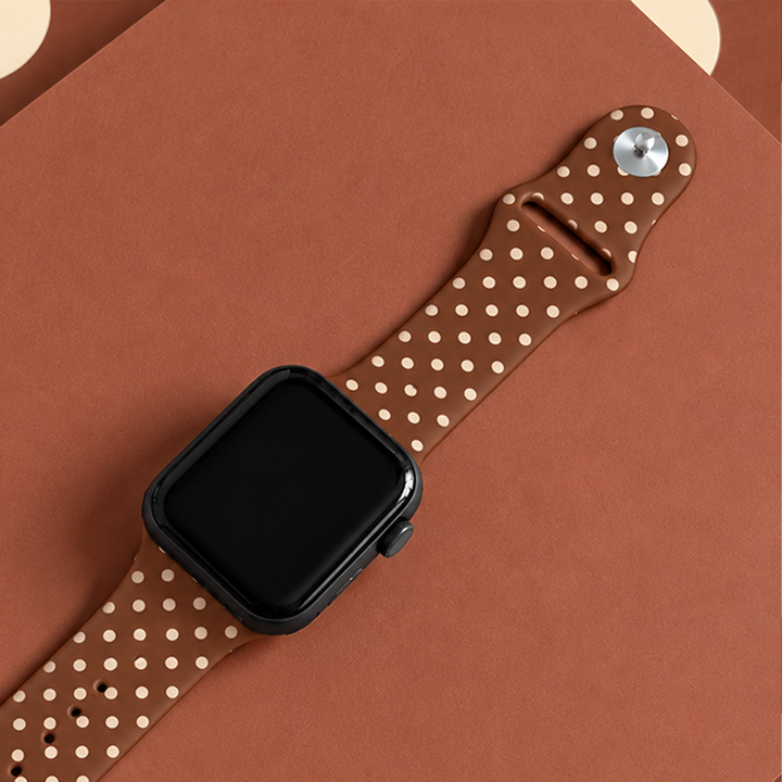 Brown silicone sport band with small cream polka dots, attached to a black Apple Watch smartwatch.