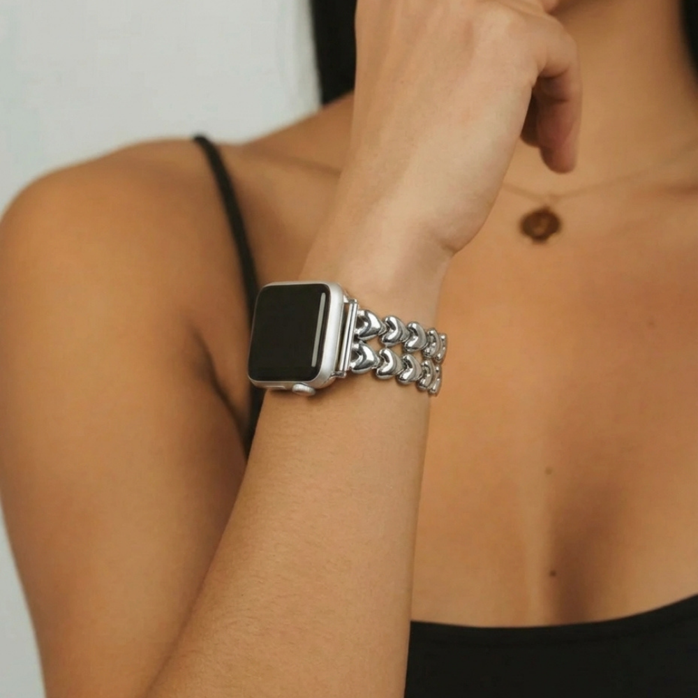 Close-up of a person wearing a Coconut Lane Hearts Chain Apple Watch Strap - Starlight, made of heart-shaped links. 