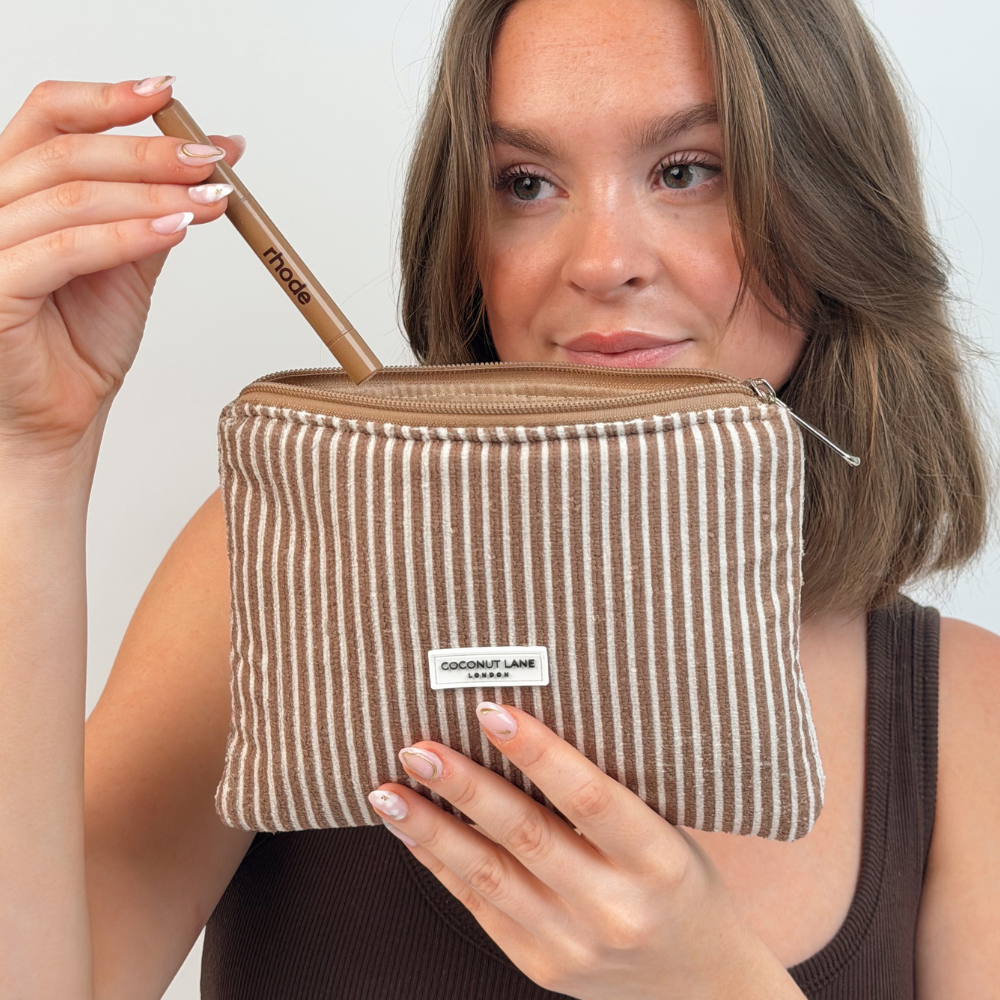 Girl posing with her mini towel everything pouch in chestnut stripes