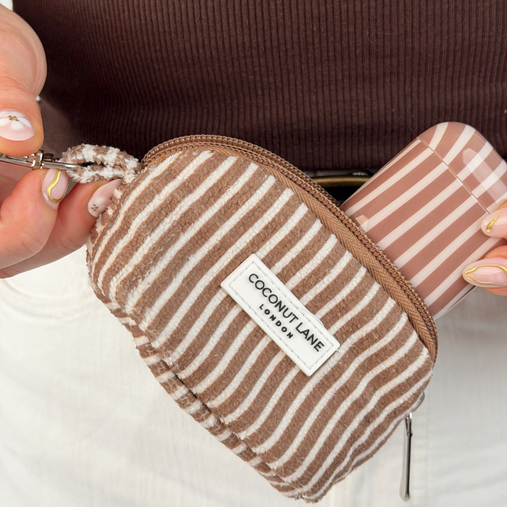 close up image of mini towel keyring bag in chestnut stripes with matching airpods