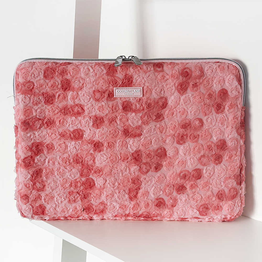 Pink floral Peony Bloom laptop sleeve by Coconut Lane, displayed upright on a white shelf.