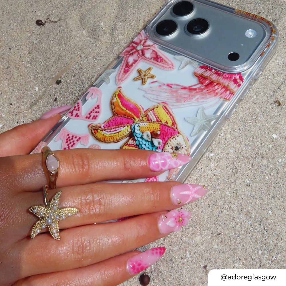 Pink Paradise Phone case with colorful designs held by a hand on sandy ground