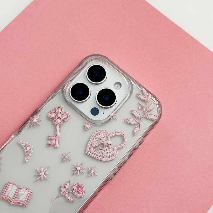 Close-up of Romance Girly Clear Phone Case showing intricate pink key, heart padlock, floral and star details with clear edges and triple camera cutouts.