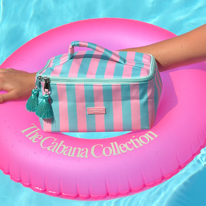 Striped Vanity Case on a pink inflatable ring with 'The Cabana Collection' text in clear water.