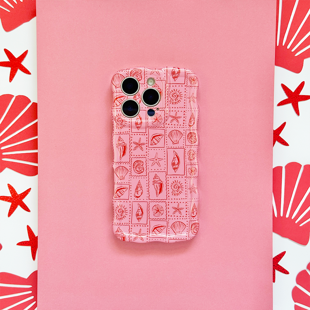 Pink phone in Coconut Lane’s wavy case with a seashell riviera design, decorated with red seashells and starfish.