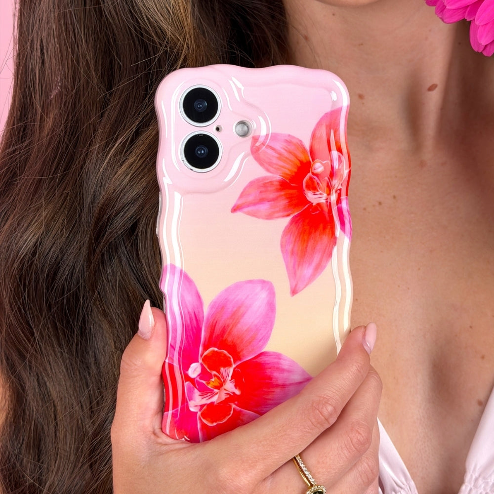 Person holding a phone with a pink and peach case with orchid on