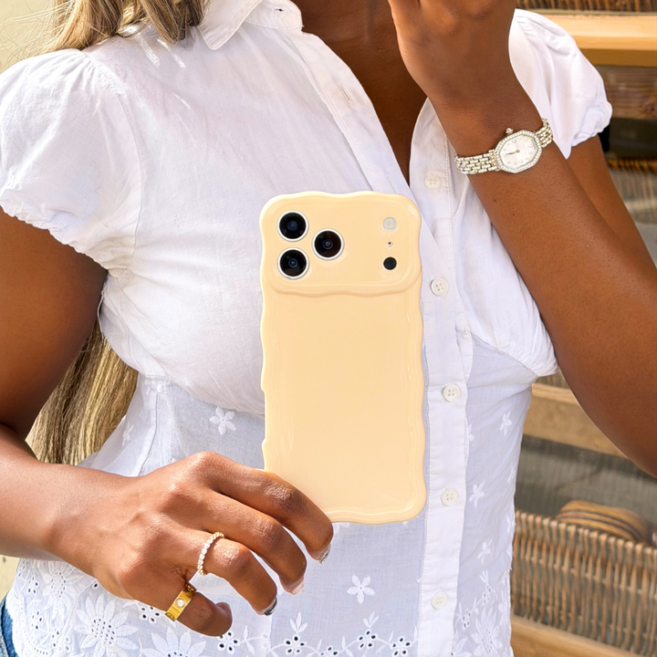 Girl holding wavy milky peach phone case next to yellow bakery