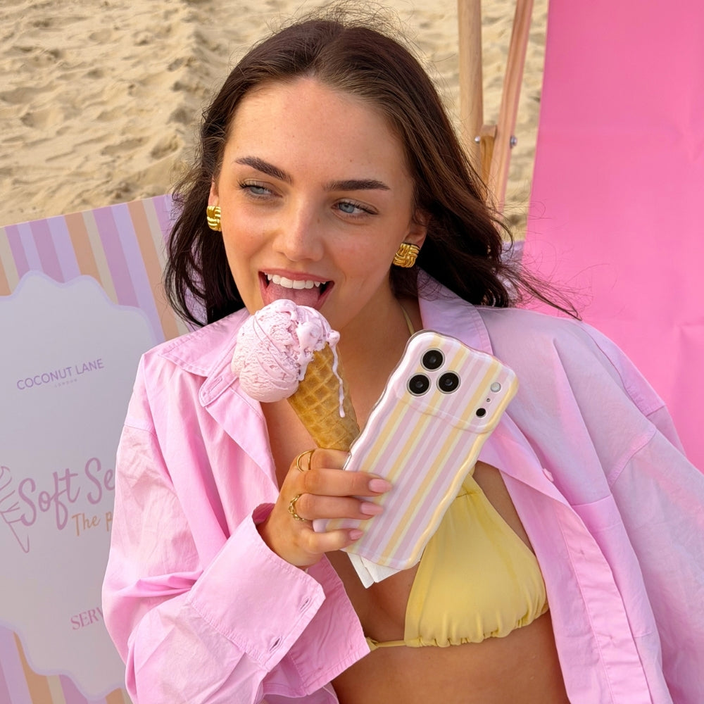 Girl licking ice cream on the beach in her bikini holding the Wavy Pastel Stripes Phone Case