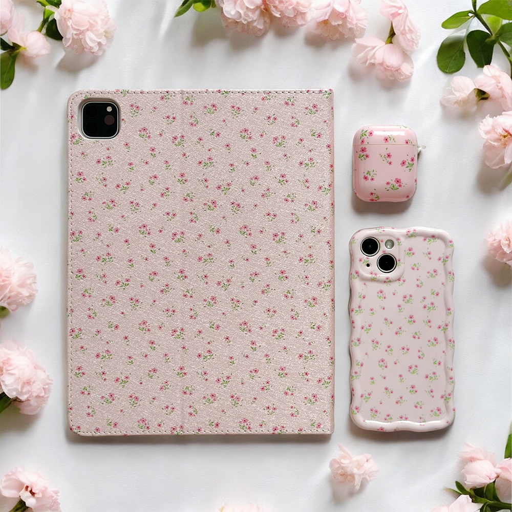 A tablet, smartphone, and AirPods case from Coconut Lane are arranged on a white surface, each adorned with a matching pink floral pattern. Pink flowers are scattered around the devices, creating a cohesive and delicate aesthetic, thanks to IMD Print Technology enhancing the Ditsy Floral Pink Airpods Case.