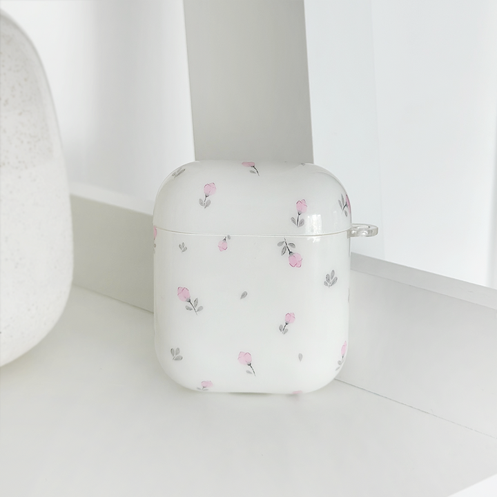 A rectangular white AirPods case from Coconut Lane, adorned with pink and gray floral patterns, rests on a white surface. The minimalist, monochromatic background complements the sleek design of this Ditsy Floral White AirPods case perfectly.