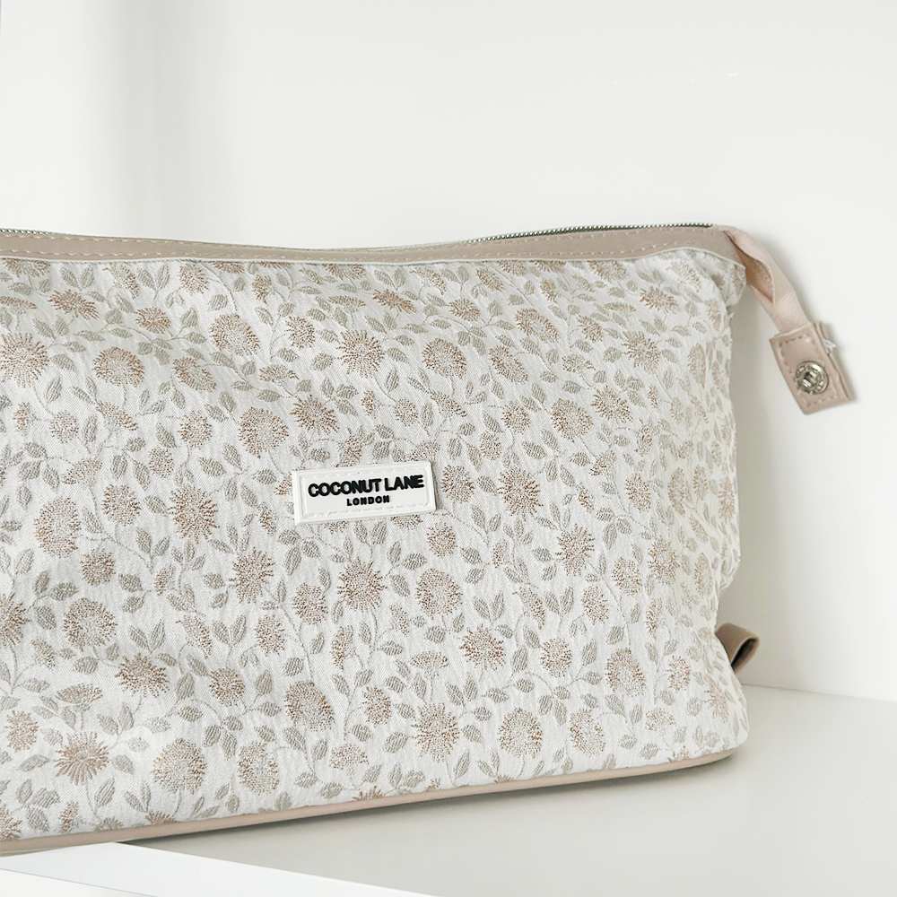 Expandable floral makeup bag by Coconut Lane, Garden Meadow design, displayed on a white shelf.