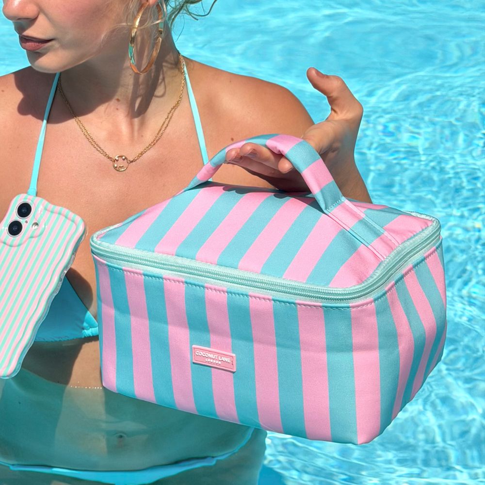 Girl holding a pink and blue striped bag by a pool